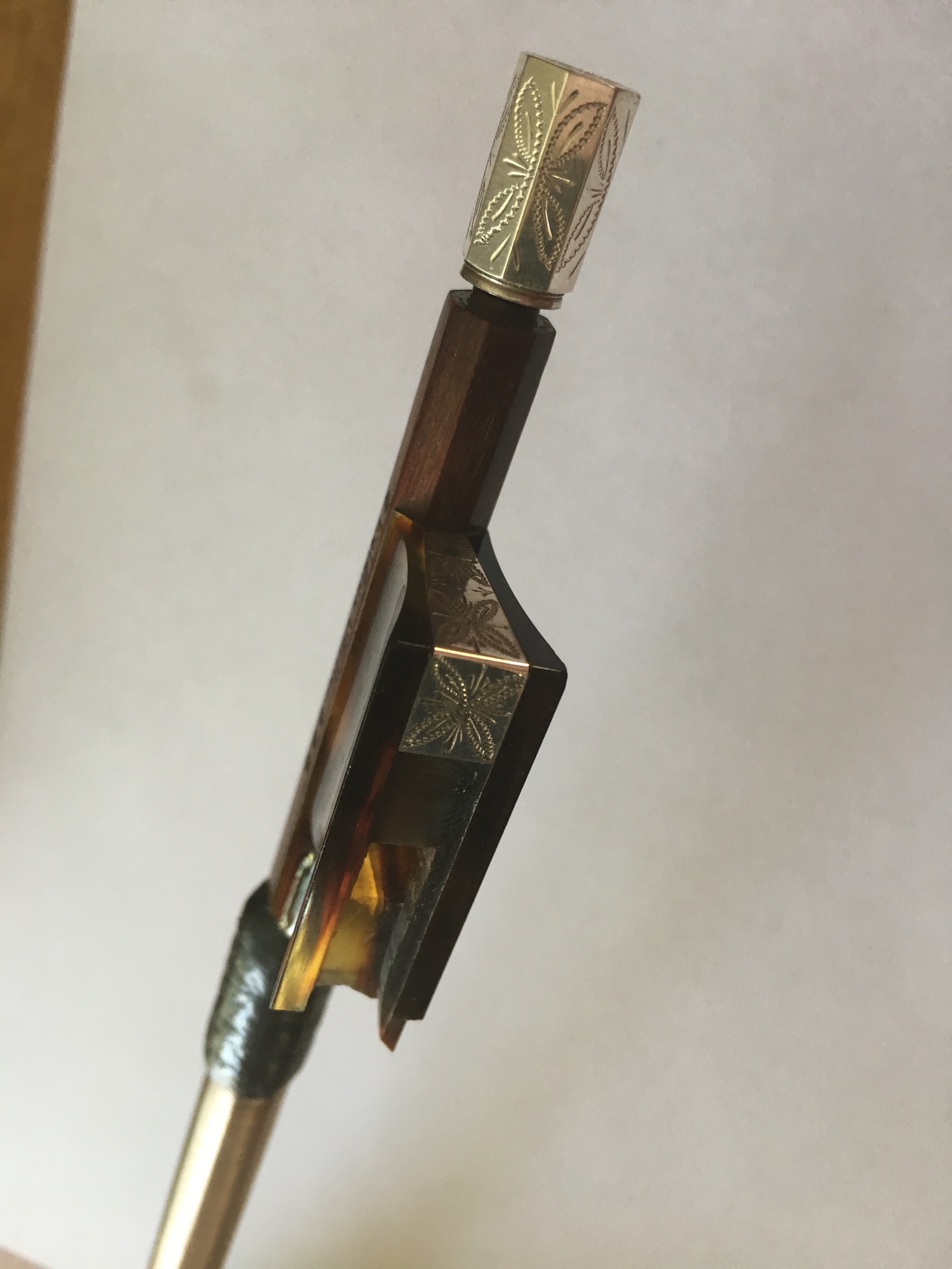 Carlos Romero holding a violin bow in workshop with tools